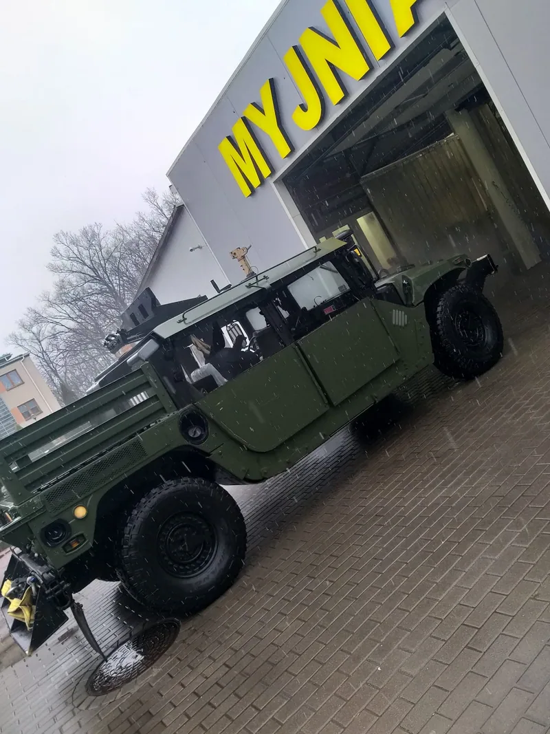 Zielony samochód terenowy przed szyldem MYJNIA
