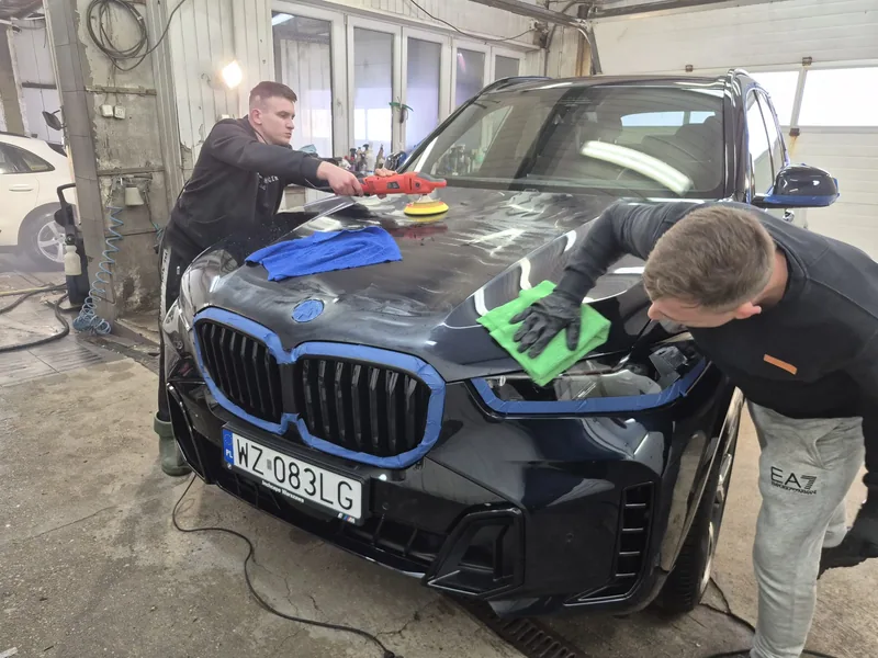 Dwóch pracowników przy masce BMW; jeden poleruje lakier w Detail-Wash