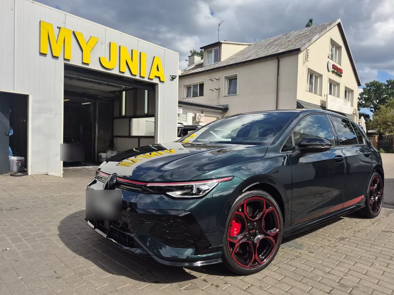 Ciemny Volkswagen Golf GTI przed szyldem MYJNIA